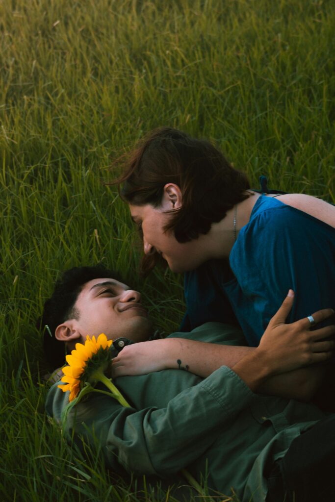 A young couple enjoying a tender moment with a sunflower in a grassy Buenos Aires park.